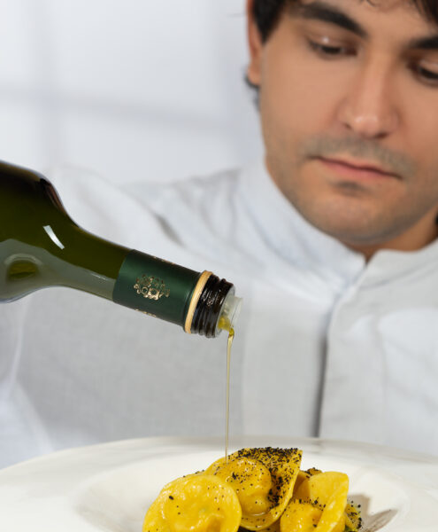 pubblicità olio extravergine versato su piatto di tortelli da uno chef