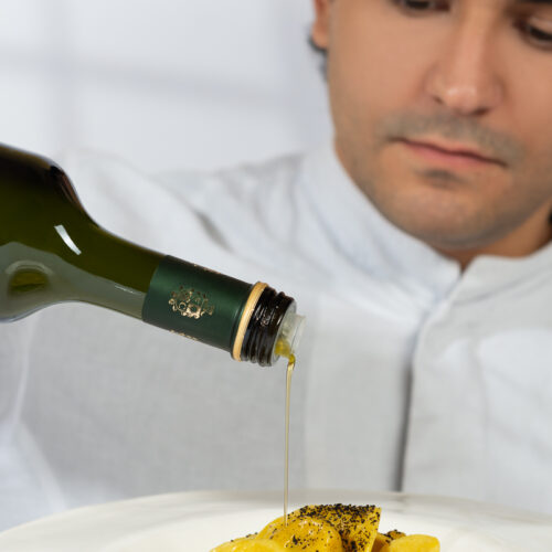 pubblicità olio extravergine versato su piatto di tortelli da uno chef